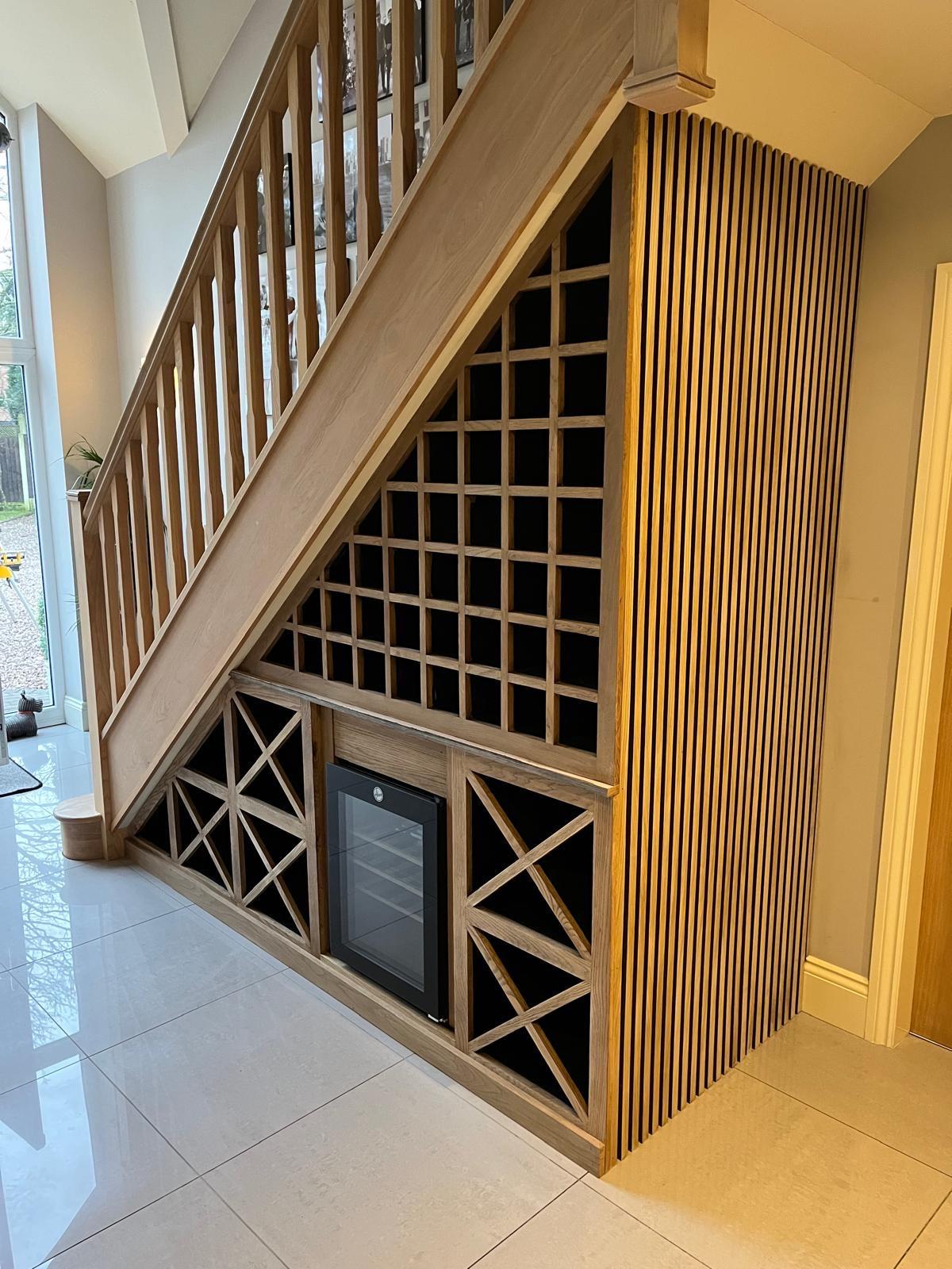 Close view of under-stairs wooden wine storage, drinks fridge and vertical timber slats